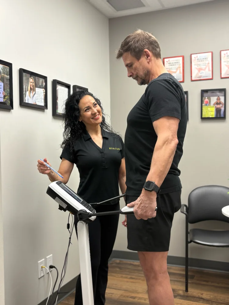 Female trainer takes weight of man by having him stand on a scale