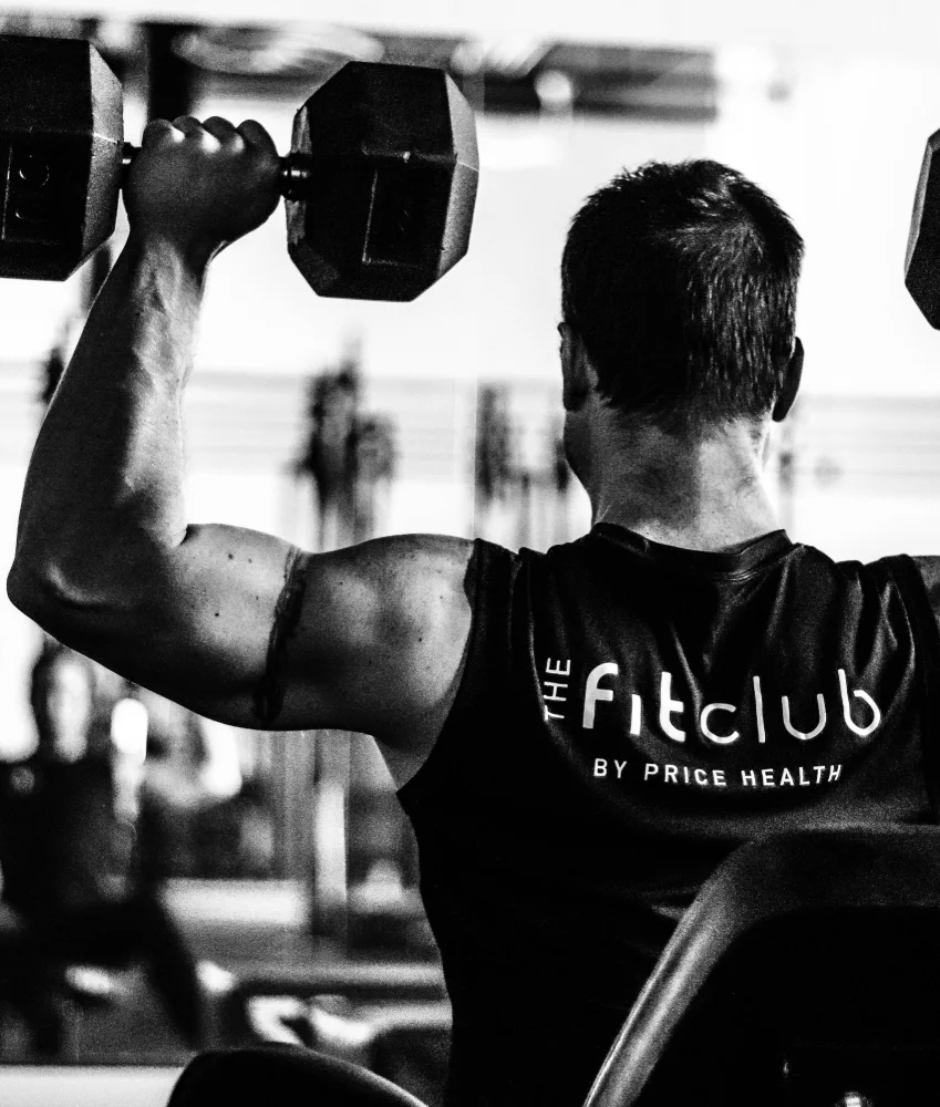 Male trainer uses dumbbells to do shoulder press exercise